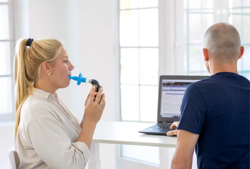 Teilnehmerin bei der Durchführung einer Spirometrie zur Messung des Lungenvolumens und der Atemkraft.