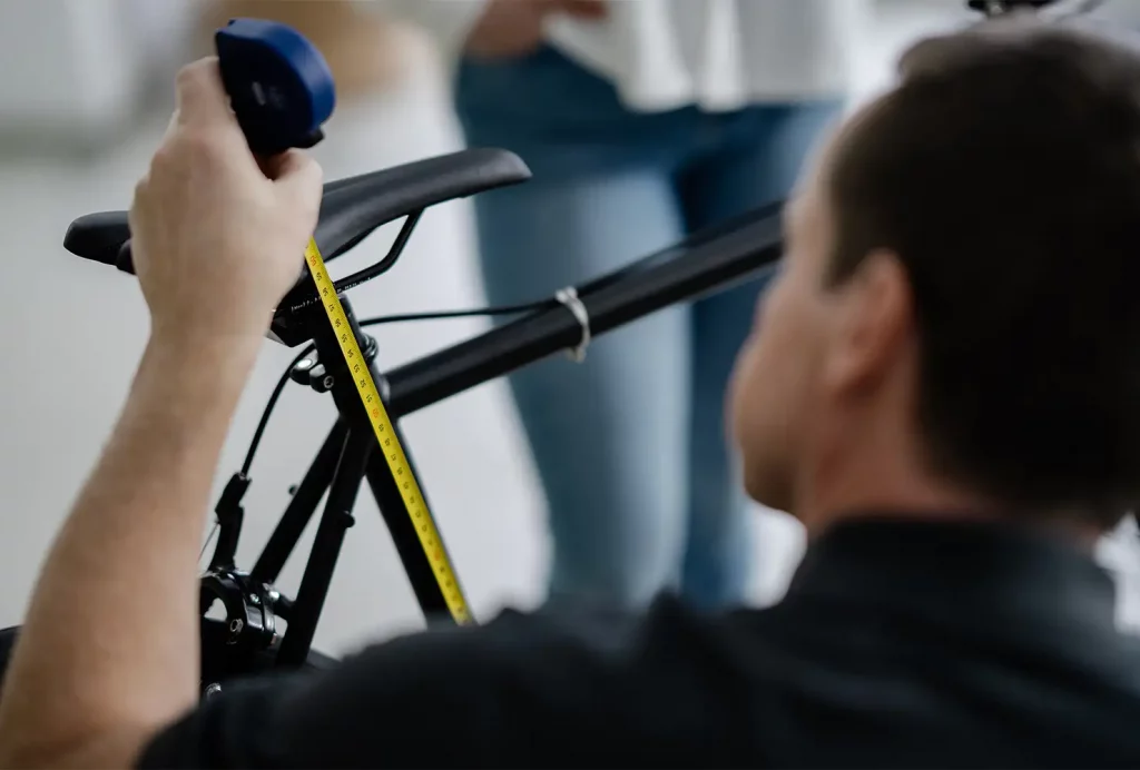 Ergonomische Sattelanpassung: Ein GiB-Trainer misst und stellt die korrekte Sattelhöhe beim Bike-Fitting einer Teilnehmerin ein.