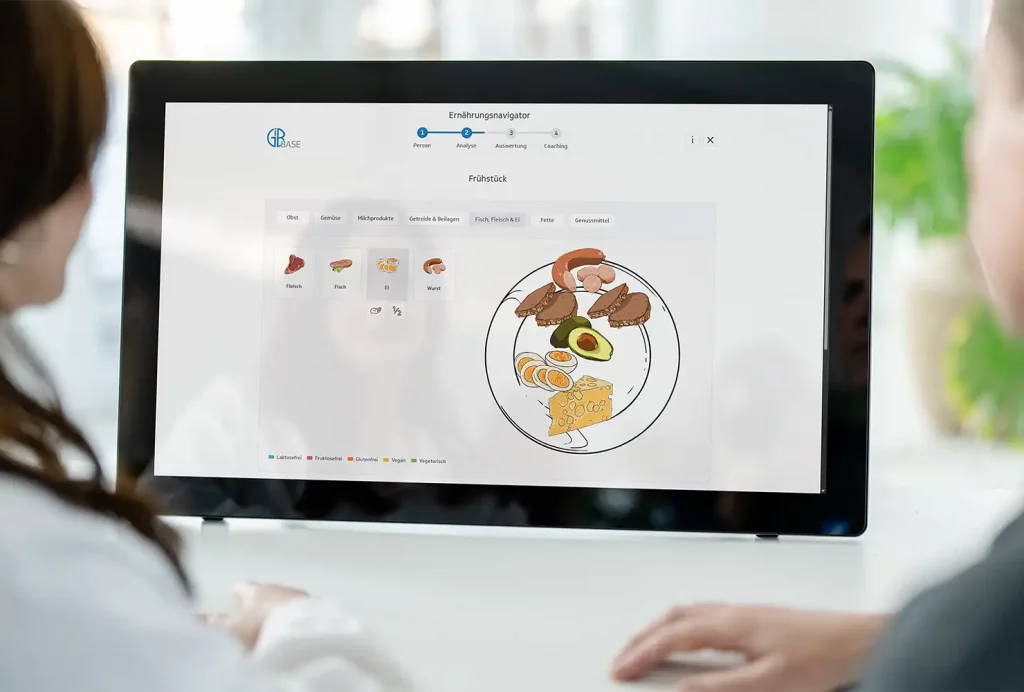 GiB-Trainer und Teilnehmerin beim digitalen Ernährungsnavigator an einem Touch-Display.