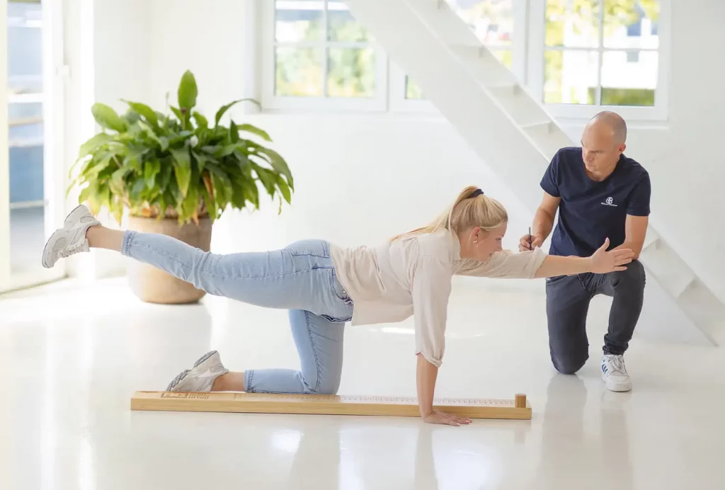 Seitenansicht der funktionalen Bewegungsanalyse: Ein GiB-Trainer bewertet die Haltungsstabilität einer Teilnehmerin.