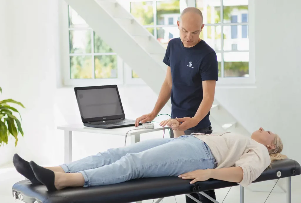 Vorbereitung der BIA-Messung: GiB-Trainer bringt Elektroden zur professionellen Körperanalyse am Handrücken einer Teilnehmerin an.