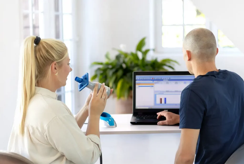 Vorbereitung zum Lungenfunktionstest: Teilnehmerin mit Spirometer erhält professionelle Einweisung durch einen GiB-Trainer.