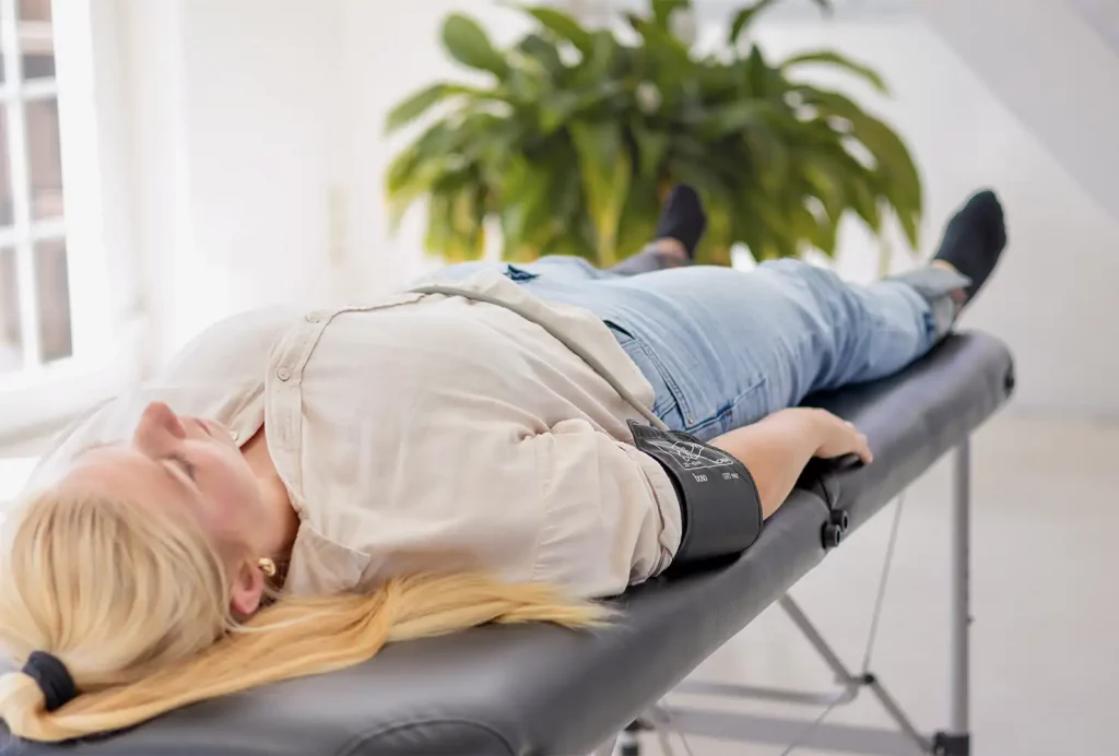 Nahaufnahme einer liegenden Teilnehmerin bei einem Gefäß-Screening mit angelegten Manschetten für die ABI-Messung.
