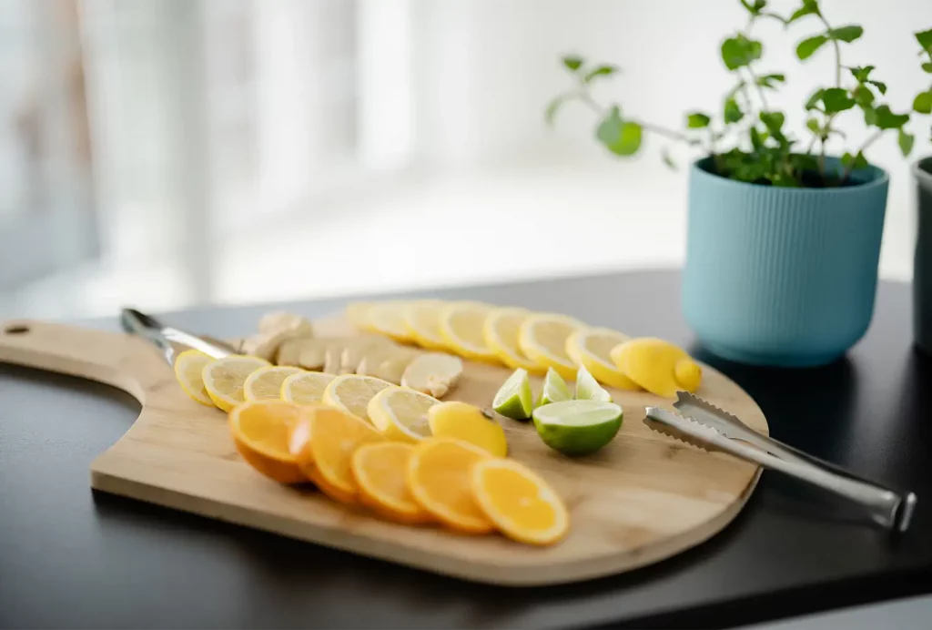 Nahaufnahme von frischen Zitronen- und Limettenscheiben auf einem Holzbrett als frische Zutaten für Infused Tea.