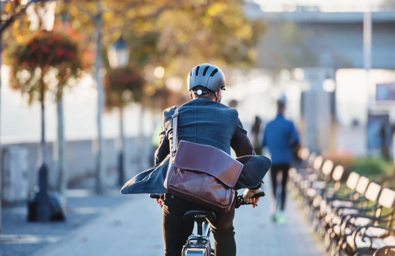 Rückansicht eines Pendlers, der mit einem Fahrrad zur Arbeit in die Stadt fährt.