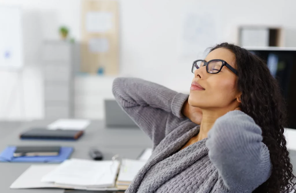 Eine Frau im Büro dehnt ihren Nacken nach langer Arbeit.