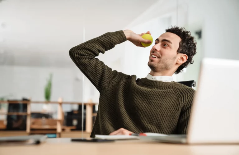 Ein Mann am Arbeitsplatz wirft einen Tennisball in die Luft.
