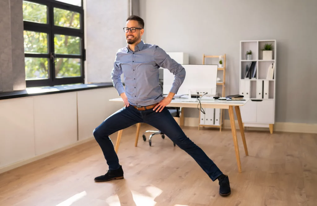 Mann bei einer Yoga-Einheit im Stehen zur Lockerung direkt am Arbeitsplatz im Büro.