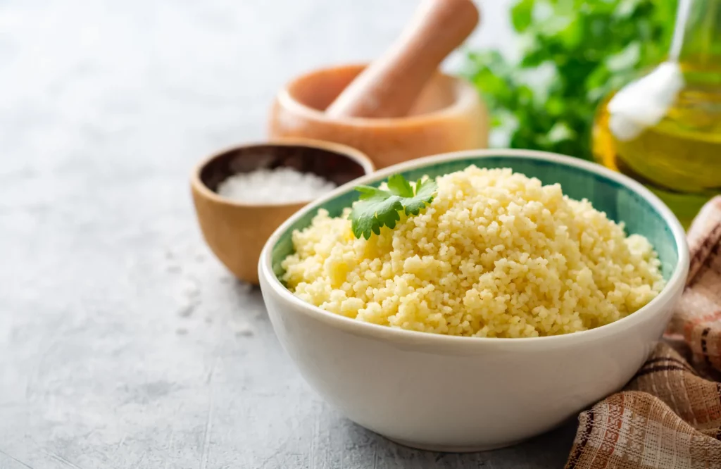 Eine Keramikschale mit Couscous, der mit frischem Koriander bestreut ist.