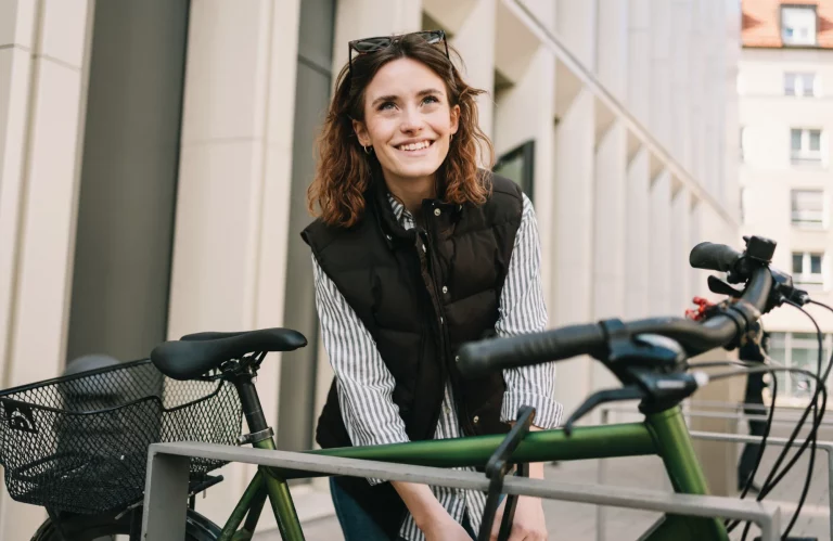 Eine Frau schließt ihr Fahrrad vor einem modernen Gebäude in der Stadt ab.
