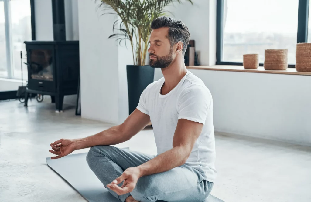 Ein Mann meditiert auf einer Yogamatte.