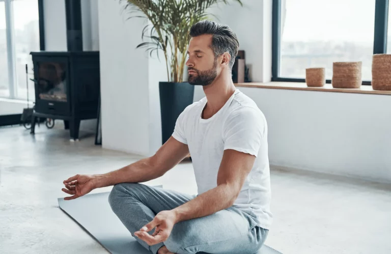 Ein Mann meditiert auf einer Yogamatte.