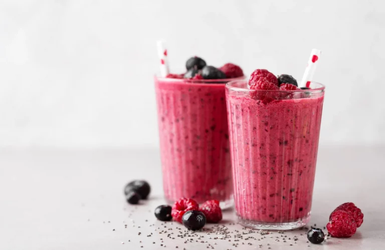 Zwei Gläser mit einem beeren Smoothie, garniert mit frischen Beeren.