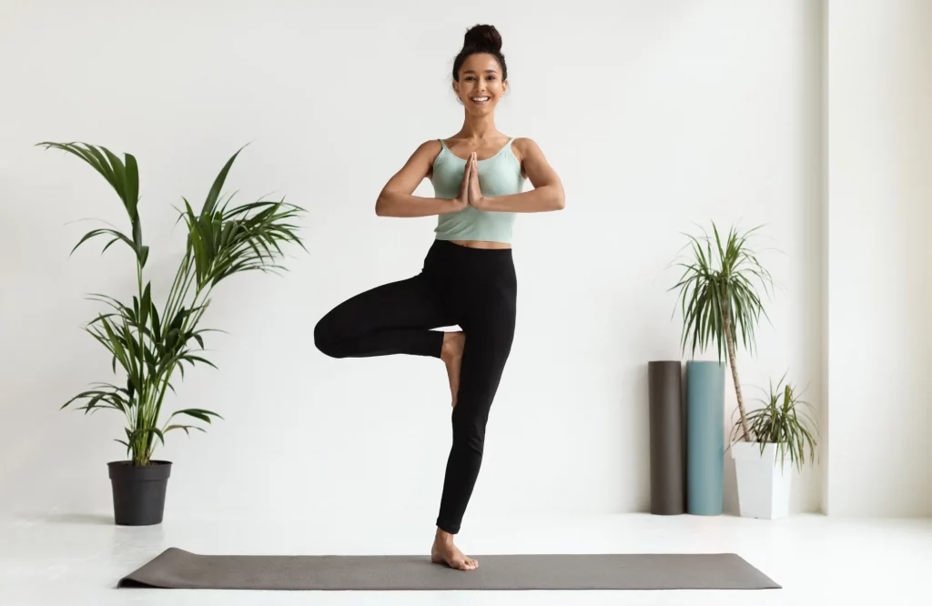 Eine Frau praktiziert die Yoga-Position „Baum“, um ihre innere Balance zu finden.