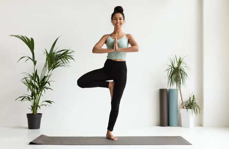 Eine Frau praktiziert die Yoga-Position „Baum“, um ihre innere Balance zu finden.